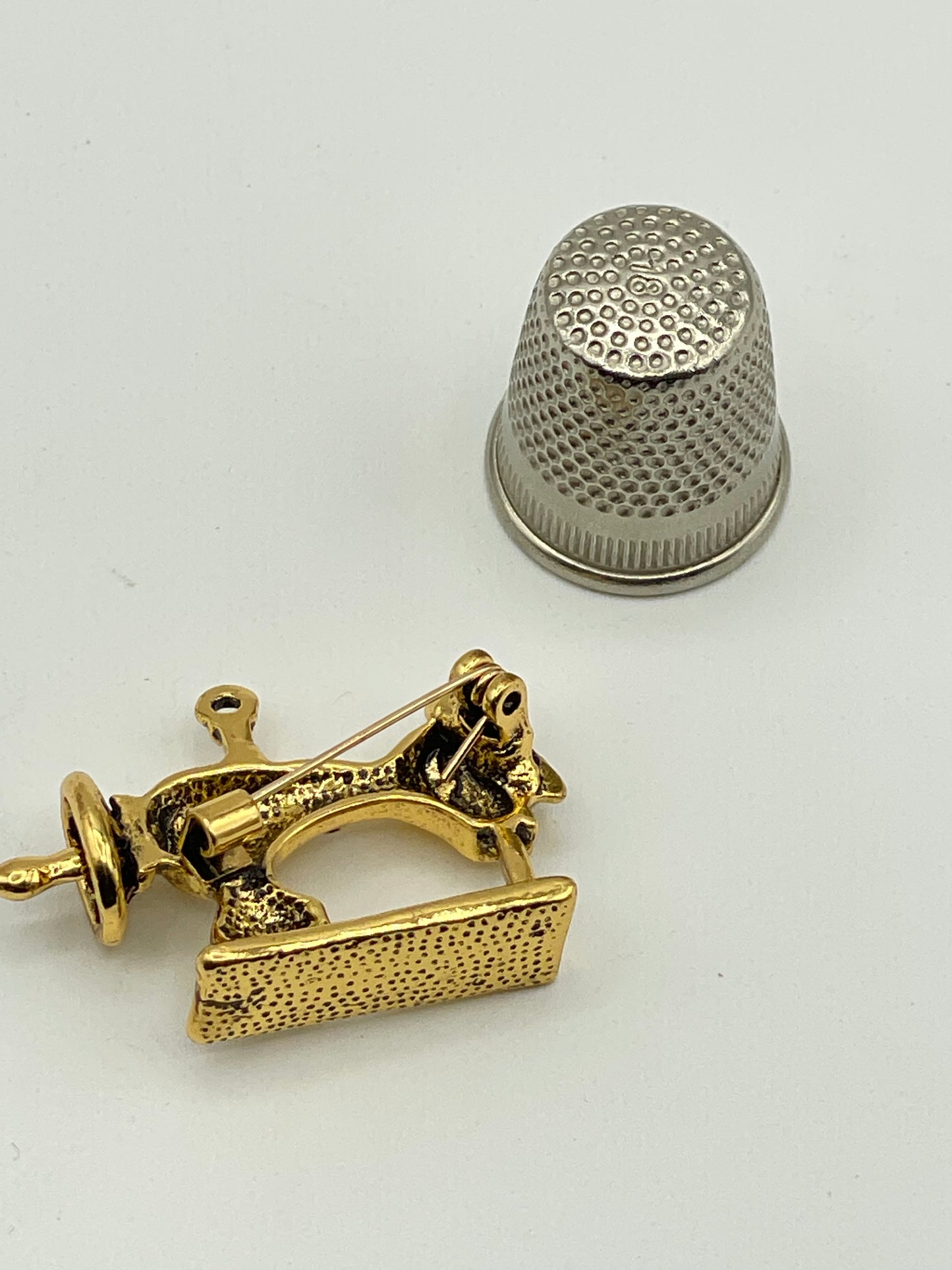 Pequeño broche de metal dorado con forma de máquina de coser