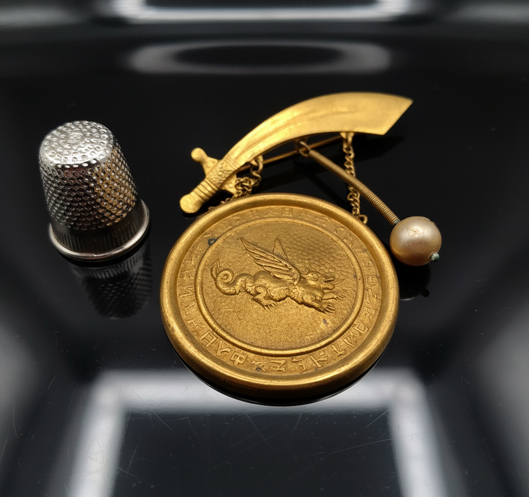 Broche vintage de metal dorado con forma de gong, dragón y espada