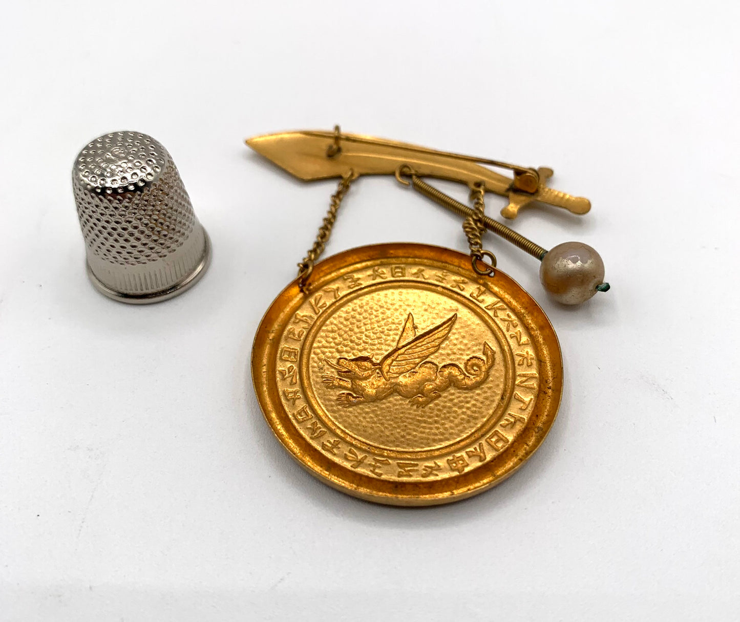 Broche vintage de metal dorado con forma de gong, dragón y espada