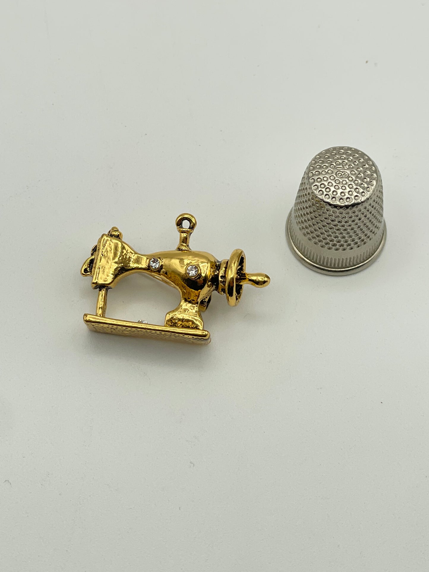 Pequeño broche de metal dorado con forma de máquina de coser