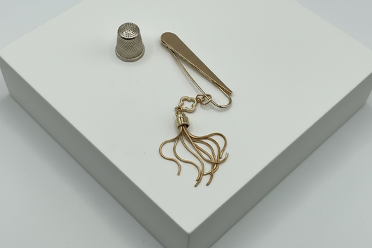 Broche tipo imperdible fantasía cabeza en forma de lágrima y fleco dorado