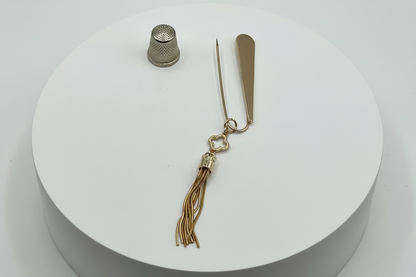 Broche tipo imperdible fantasía cabeza en forma de lágrima y fleco dorado