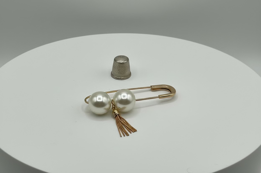 Broche tipo imperdible fantasía con dos bolas nacaradas y borla dorada