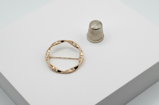 Broche tipo imperdible fantasía con forma circular trenzada