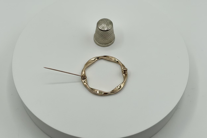 Broche tipo imperdible fantasía con forma circular trenzada