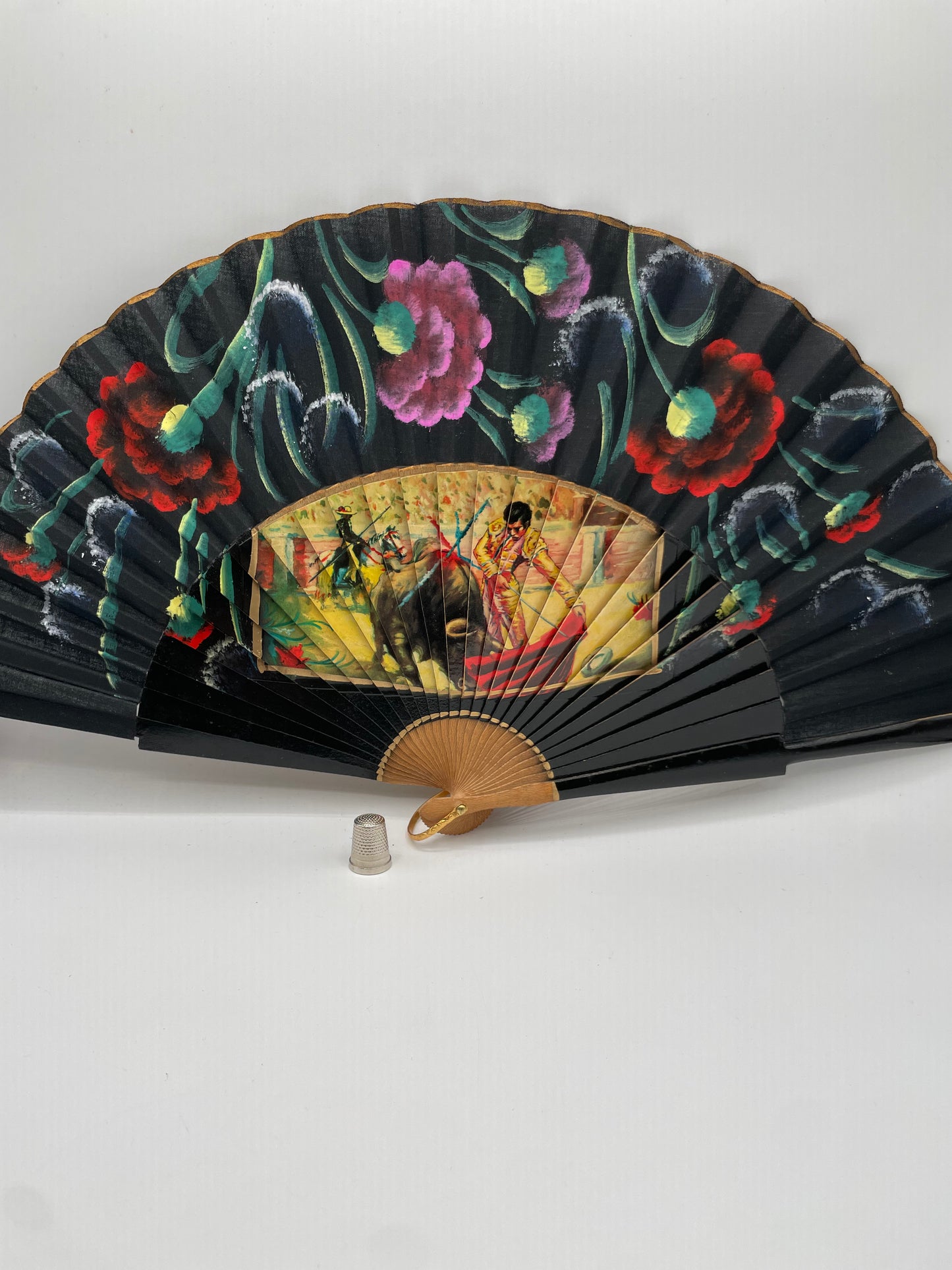 Abanico de madera, pintado a mano color negro con coloridas flores e imagen impresa de motivos taurinos