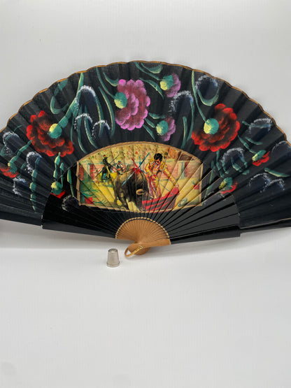 Abanico de madera, pintado a mano color negro con coloridas flores e imagen impresa de motivos taurinos