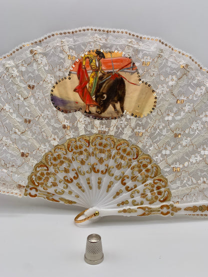 Abanico de pasta color blanco nácar, encaje blanco y dorado con imagen impresa de torero